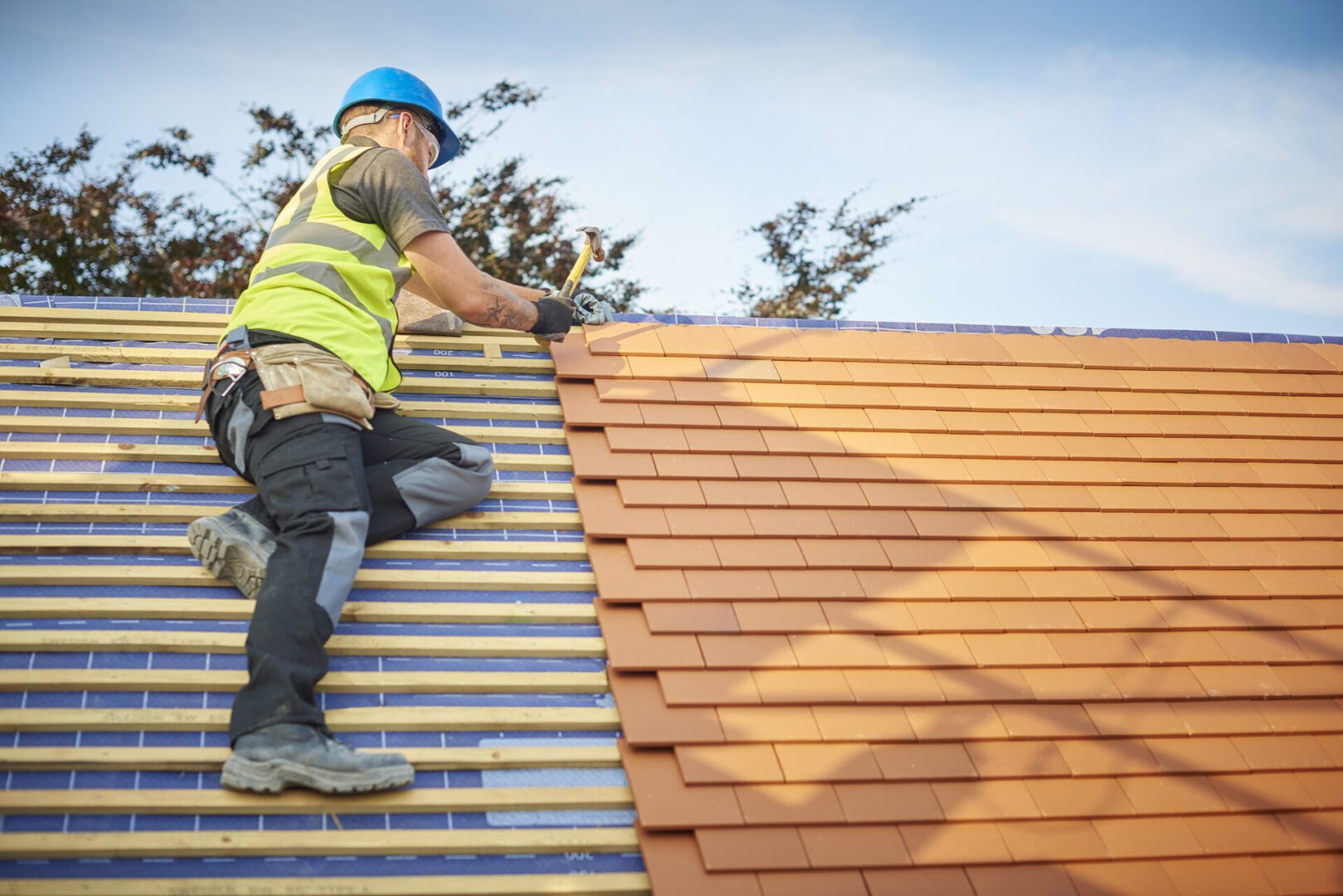 Man hammering shingles on roof