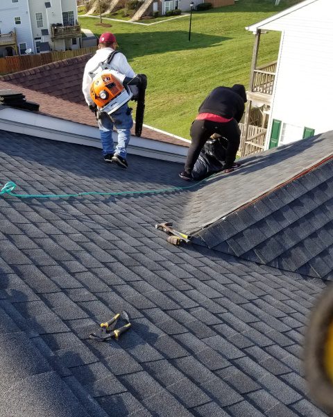 Two men fixing rooftop shingles